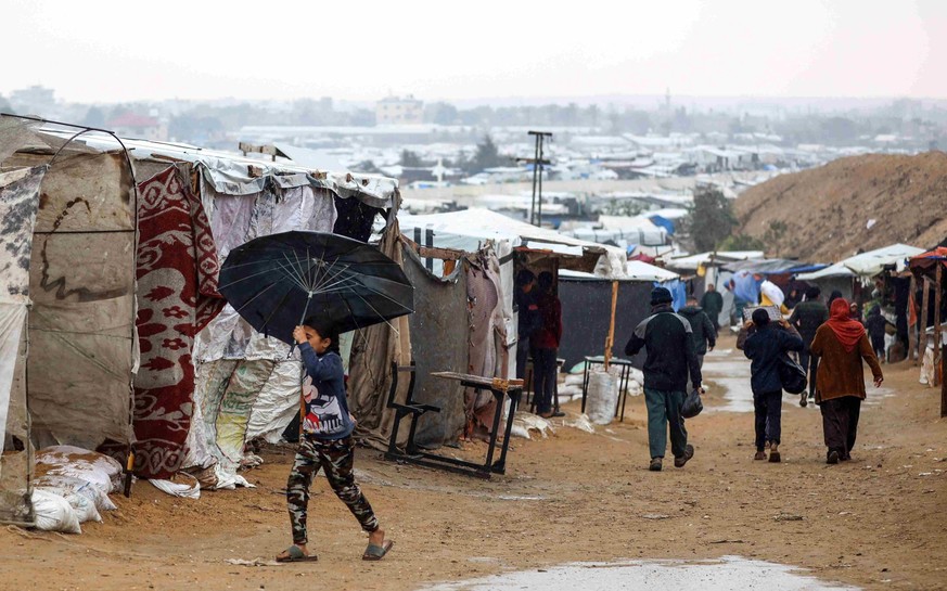 Une fillette palestinienne tient un parapluie pour se protéger de la pluie dans un camp de fortune à Khan Younès, dans la bande de Gaza.