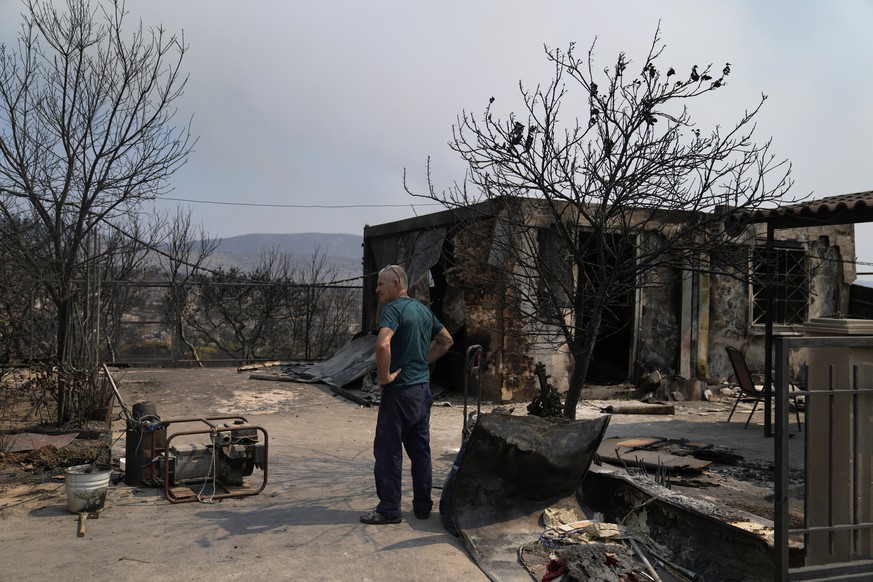 A man stands by a burned down house after yesterday's blaze in Mandra west of Athens, on Wednesday, July 19, 2023. Fast-moving wildfires raged over hills in the scorching heat outside the Greek capital...