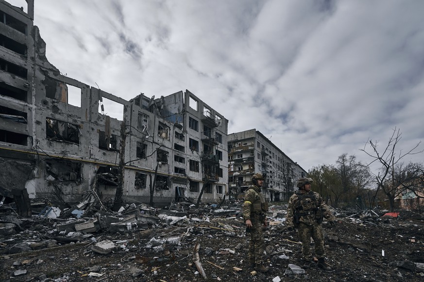Ukrainian soldiers pass by houses ruined in the Russian shelling in Bakhmut, Donetsk region, Ukraine, Thursday, Nov. 10, 2022. (AP Photo/LIBKOS)