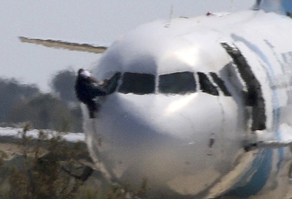 An unidentified man stuggles with another as he climbs out of the cockpit window of the hijacked Egyptair Airbus A320 at Larnaca Airport in Larnaca, Cyprus, March 29, 2016 REUTERS/Yiannis Kourtoglou T ...