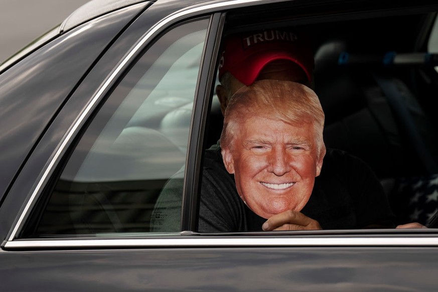 WASHINGTON, DC - AUGUST 3: A supporter of former U.S. President Donald Trump holds up a cutout of Trump as rides in a limousine near the E. Barrett Prettyman United States Courthouse August 3, 2023 in ...
