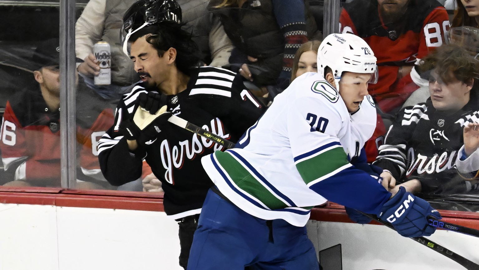 Vancouver Canucks center Curtis Lazar (20) checks New Jersey Devils defenseman Jonas Siegenthaler (71) during the third period of an NHL hockey game Monday, Feb. 6, 2023, in Newark, N.J. (AP Photo/Bil ...