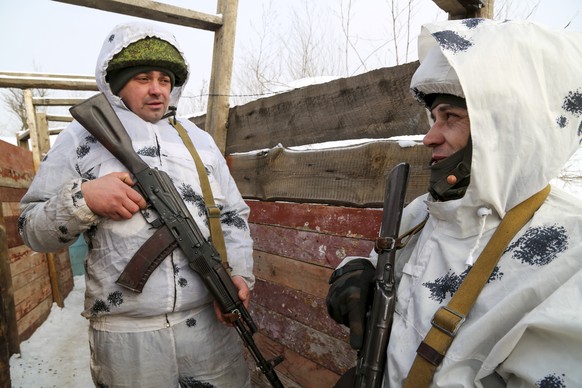Servicemen hold their Kalashnikov rifles as they talk to each other in a trench on the territory controlled by pro-Russian militants on the frontline with Ukrainian government forces near Spartak vill ...