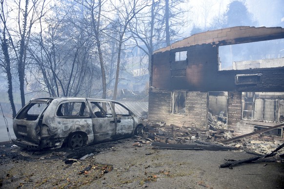 A home and vehicle are damaged from the wildfires around Gatlinburg, Tenn., on Tuesday, Nov. 29, 2016. Rain had begun to fall in some areas, but experts predicted it would not be enough to end the rel ...