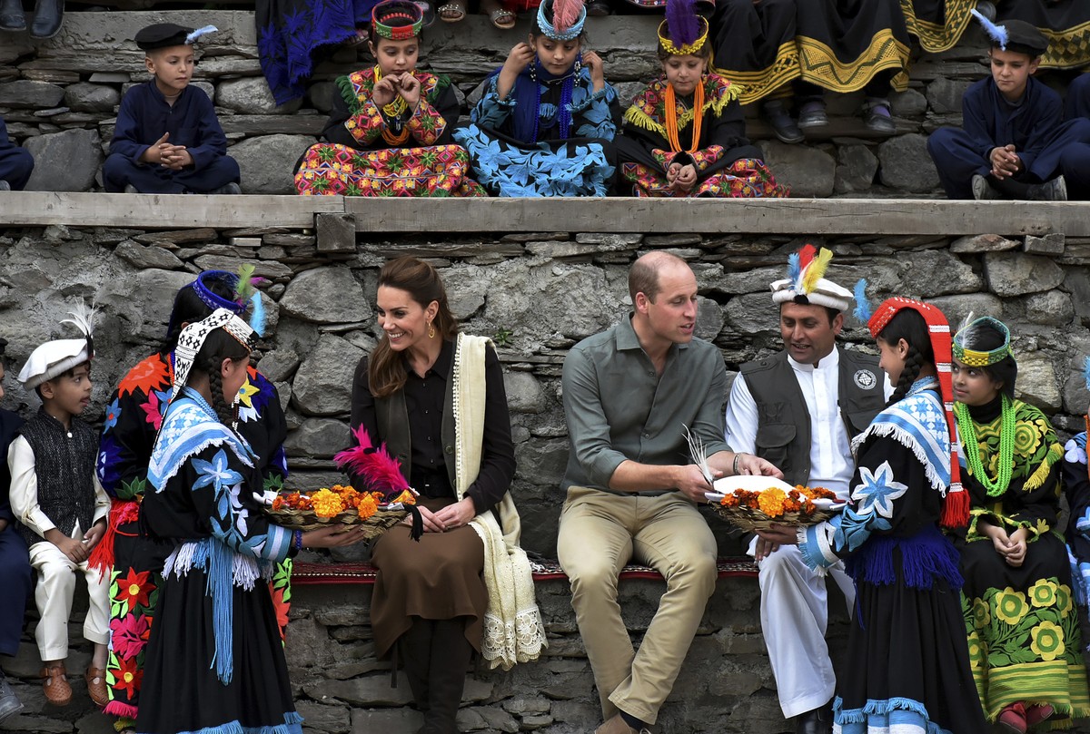 In this photo released by Press Information Department, Members of Kalash community greet Britain's Prince William, center, and his wife Kate to presents and traditional caps during their visit t ...