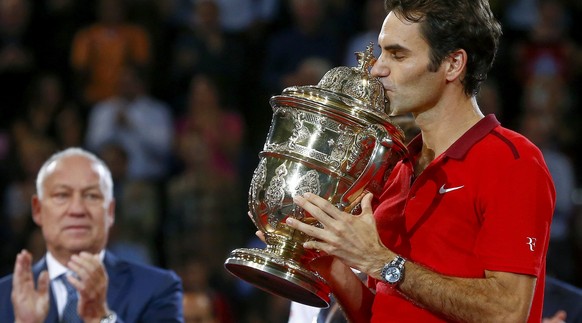 Federer mit der Siegertrophäe 2014 – Turnierboss Brennwald applaudiert im Hintergrund.