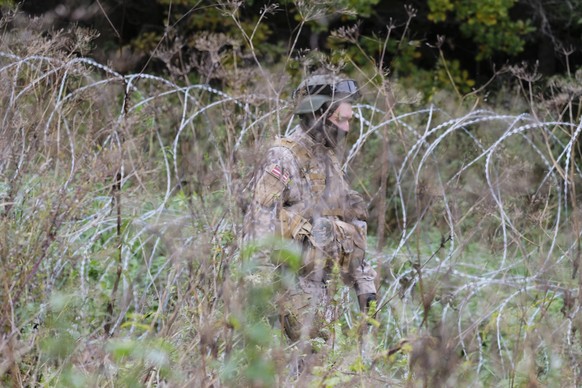 epa09493129 A soldier of Latvian National Armed Forces (NAF) patrols along a new barbed wire fence, donated by the Slovenian Ministry of Defense, on the state border with Belarus in Kraslava region, L ...