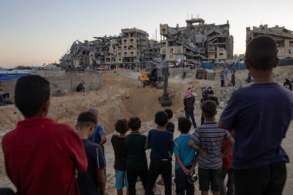 KEYPIX - epa12486652 Palestinians watch as machinery and workers from Egypt search the rubble of damaged buildings for the bodies of hostages in the Hamad City area of Khan Yunis, southern Gaza Strip, ...