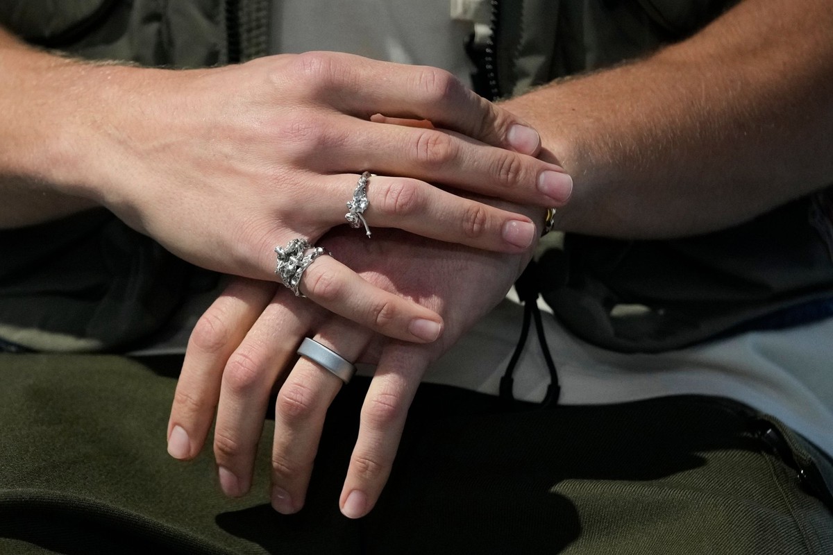 Cette dualité se manifeste également sur ses mains: d'un côté, des bijoux artistiques, de l'autre, un outil qui mesure ses données de performance.