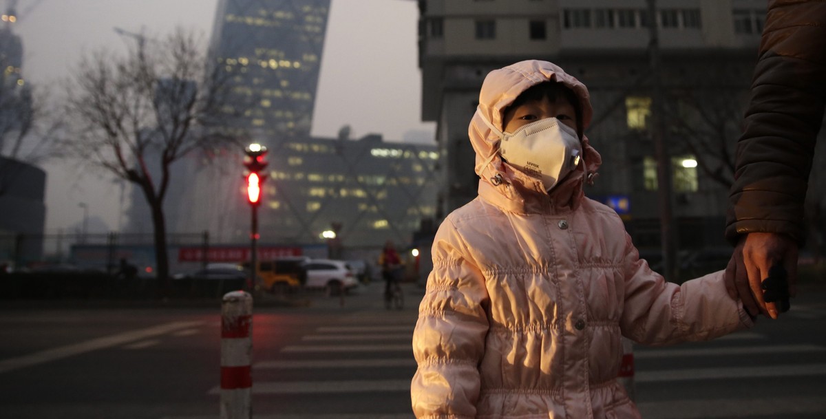 epa05057972 A woman wears a mask on a street shrouded in smog in Beijing, China, 07 December 2015.Beijing's education authorities ordered all of the city's primary and middle school students ...
