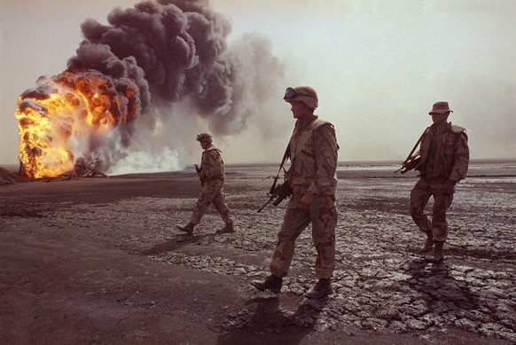 FILE -- In this March 7, 1991 file photo, a U.S. Marine patrol walks across the charred oil landscape near a burning well during perimeter security patrol near Kuwait City. Twenty five years after the ...