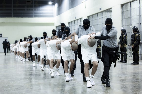 FILE - In this photo provided by El Salvador&#039;s presidential press office, prison guards transfer deportees from the U.S., alleged to be Venezuelan gang members, to the Terrorism Confinement Cente ...