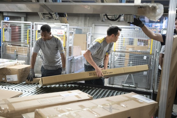 Bahlibi, recognised refugee from Eritrea, left, and Esmail, from Afghanistan, at work in the Haerkingen parcel centre as part of the integration apprenticeship (INVOL) to become a logistics specialist ...