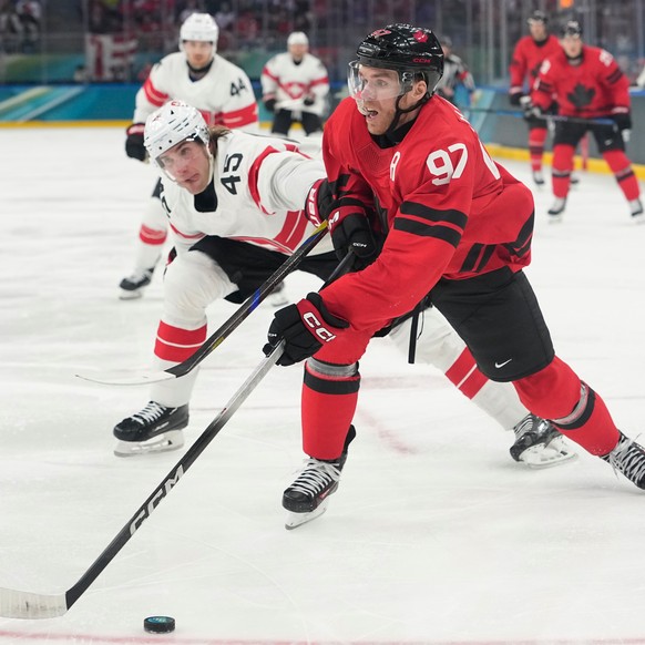 Switzerland's Michael Fora, left, challenges Canada's Connor McDavid during a preliminary round match of men's ice hockey between Canada and Switzerland at the 2026 Winter Olympics, in  ...