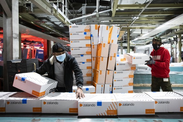 Angestellte der Post packen angelieferte Pakete der Firma Zalando auf ein Laufband im Paketzentrum Haerkingen, am Mittwoch, 9. Dezember 2020, in Haerkingen. (KEYSTONE/Peter Klaunzer)