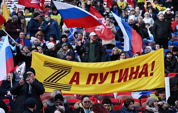 epa09833532 People hold a banner with letter Z and saying &#039;For Putin!&#039; during a concert marking the 8th anniversary of Crimea&#039;s reunification with Russia at the Luzhniki stadium in Mosc ...