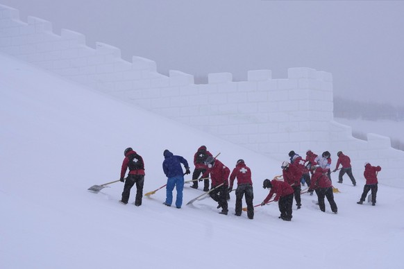 Volunteers clear the course as the start of the women&#039;s slopestyle qualification has been delayed due to a weather consition at the 2022 Winter Olympics, Sunday, Feb. 13, 2022, in Zhangjiakou, Ch ...