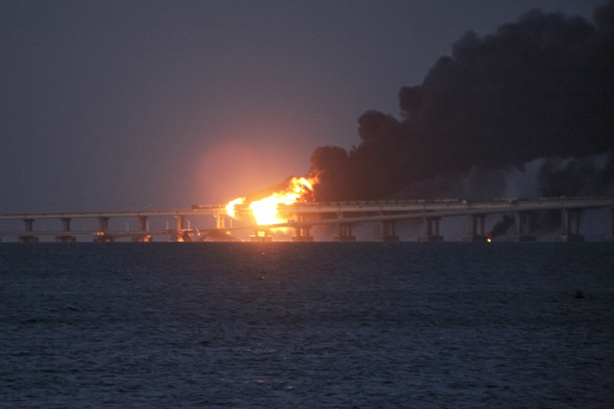 Flame and smoke rise from the Crimean Bridge connecting Russian mainland and the Crimean peninsula over the Kerch Strait, in Kerch, Crimea, early Saturday, Oct. 8, 2022. Russian authorities say a truc ...