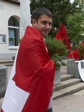 Anian Liebrand von der jungen SVP posiert mit Schweizer Fahne an einer bewilligten Protestveranstaltung der JUSO gegen die Bilderberg-Konferenz, in St. Moritz am 11. Juni 2011