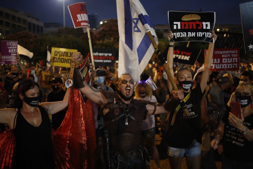 Protesters hold signs during a demonstration against Israel&#039;s government in Rabin square in Tel Aviv, Israel, Saturday, July 11, 2020. Thousands of Israelis gathered Saturday to protest the new g ...