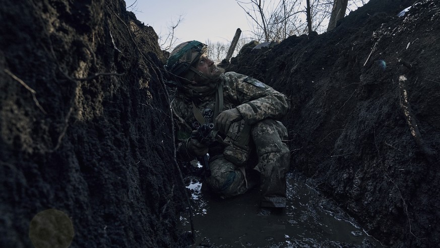 A Ukrainian soldier takes cover in a trench under Russian shelling on the frontline close to Bakhmut, Donetsk region, Ukraine, Sunday, March 5, 2023. (AP Photo/Libkos)