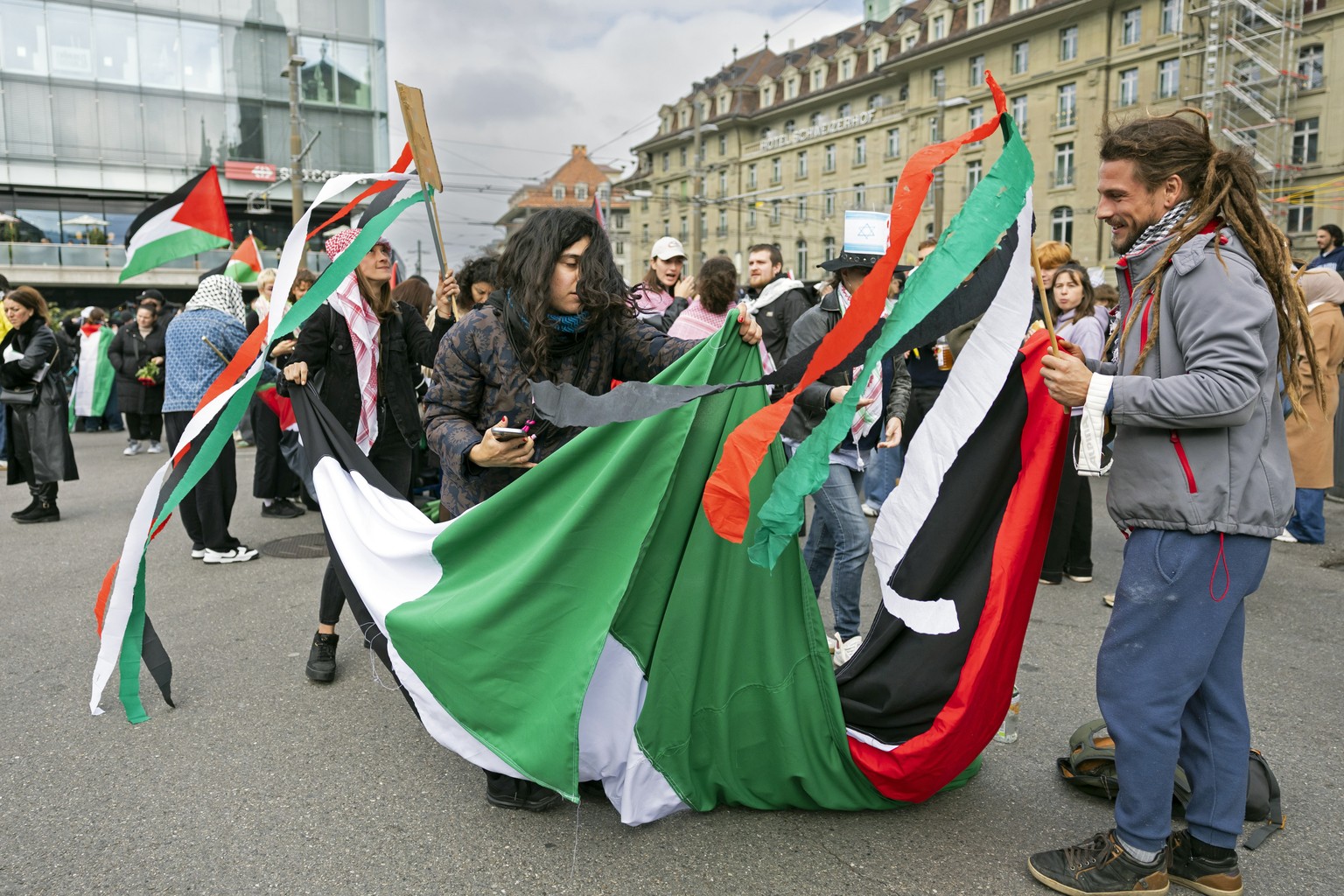 epa12446751 People hold banners in the colors of the Palestinian flag and wave flags during an unauthorized rally in solidarity with the Palestinian people in Bern, Switzerland, 11 October 2025. EPA/P ...