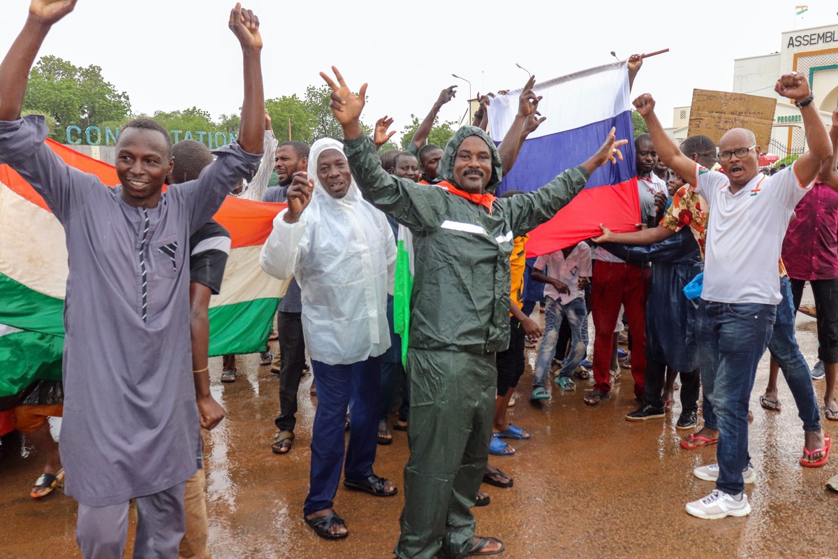 epa10771228 Supporters of putschist soldiers hold Niger's flags as they celebrate outside the National Assembly building in Niamey, Niger, 27 July 2023. Mutinous soldiers calling themselves the N ...