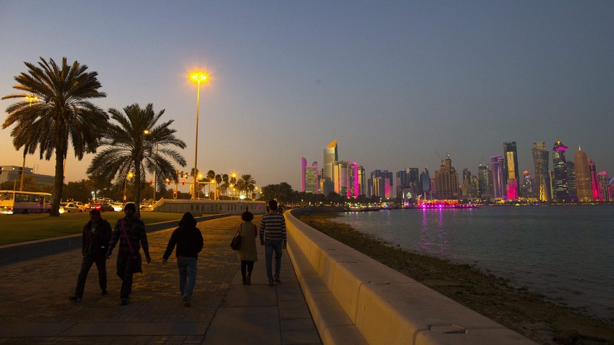 epa04591688 People walk on the corniche promenade in front of the skyline of Doha&#039;s West Bay high rise buildings at sunset, Doha, Qatar, 28 January 2015. The men&#039;s Handball World Championshi ...