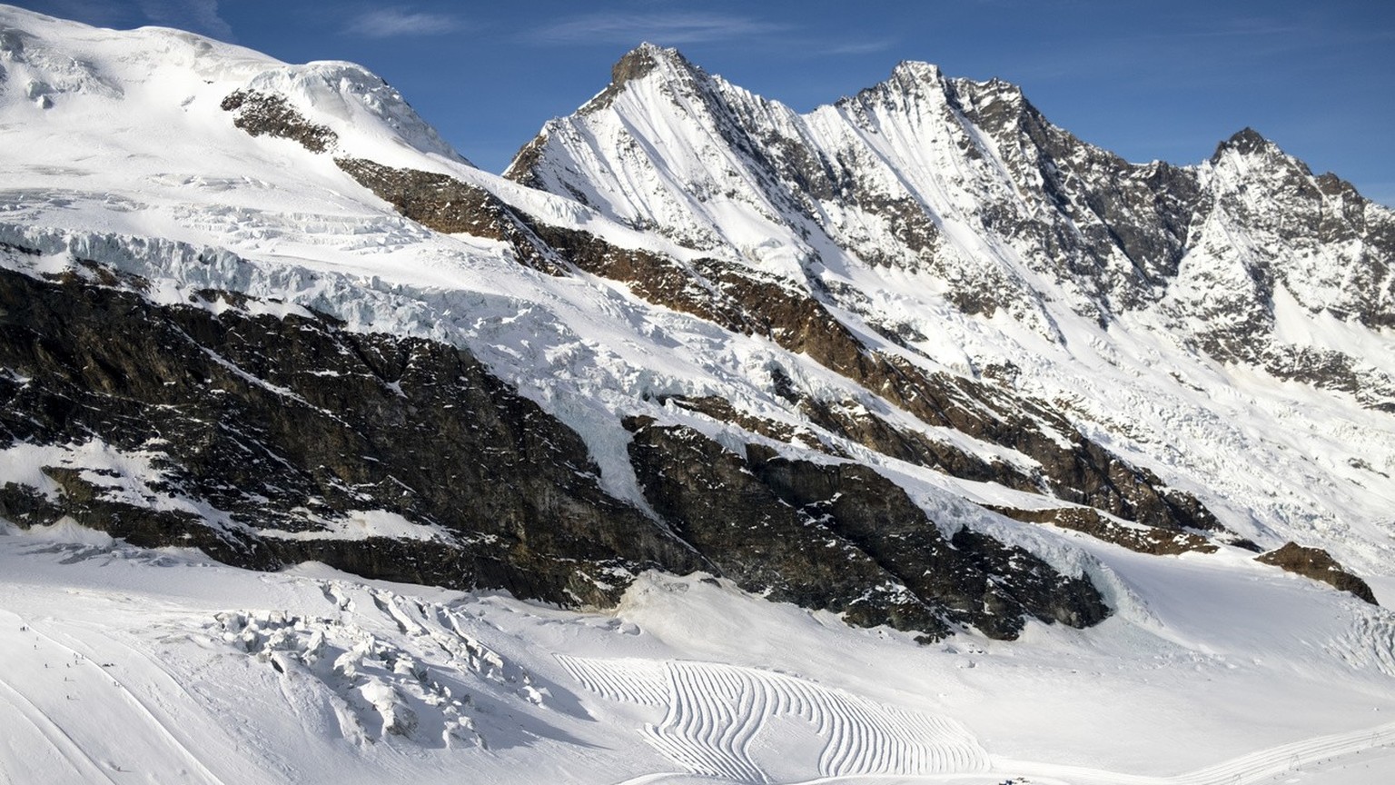 Des skieurs skient sur les pistes de ski du Glacier de Fee devant le massif des montagnes des Mischabels ce vendredi 17 fevrier 2023 a Saas-Fee. (KEYSTONE/Laurent Gillieron)