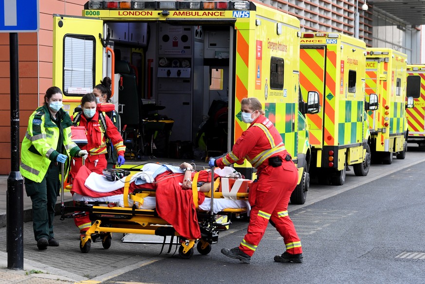 epa08916748 Ambulance workers assist a patient outside the Royal London Hospital in London, Britain, 03 January 2021. Coronavirus cases are continuing to surge across England with hospital admissions  ...