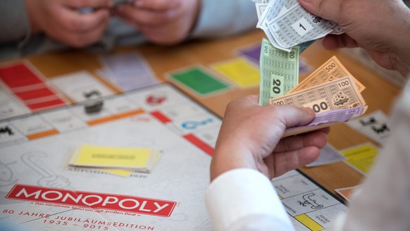 epa04822753 A player holds toy money while fighting for supremacy on a &#039;Monopoly&#039; game board during the final of the German Monopoly Championships in Berlin, Germany, 28 June 2015. Developed ...