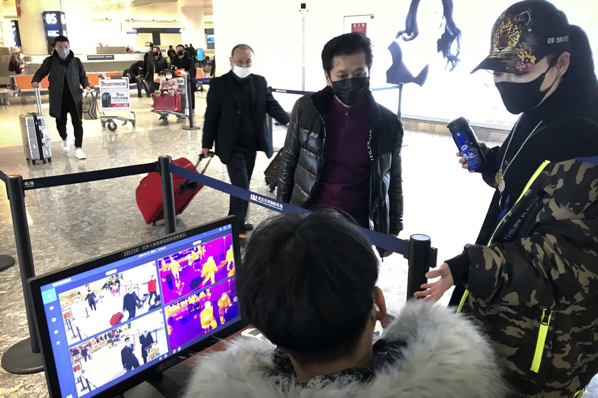 Travelers pass through a health screening checkpoint at Wuhan Tianhe International Airport in Wuhan in southern China's Hubei province, Tuesday, Jan. 21, 2020. A fourth person has died in an outb ...