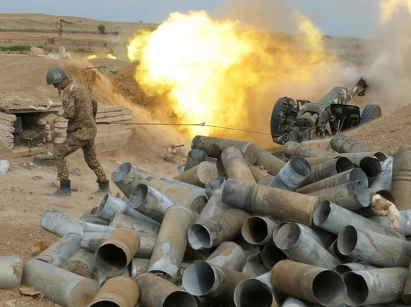 HANDOUT - Ein Soldat der armenischen Armee feuert eine Kanone ab in der Region Berg-Karabach. Die Zusammenst