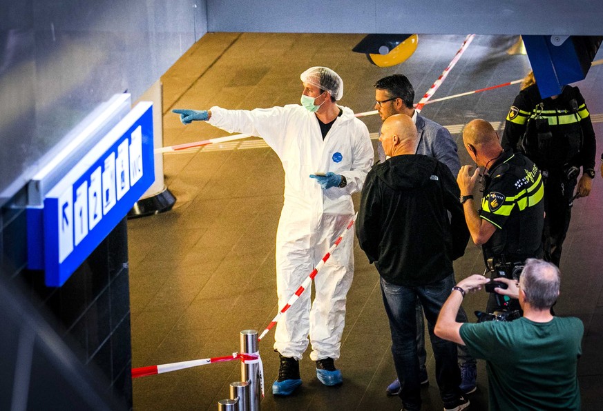 epa06988291 Police investigators stand together near the crime scene at the central train station after a stabbing incident in Amsterdam, Netherlands, 31 August. The Police have shot a suspect after t ...