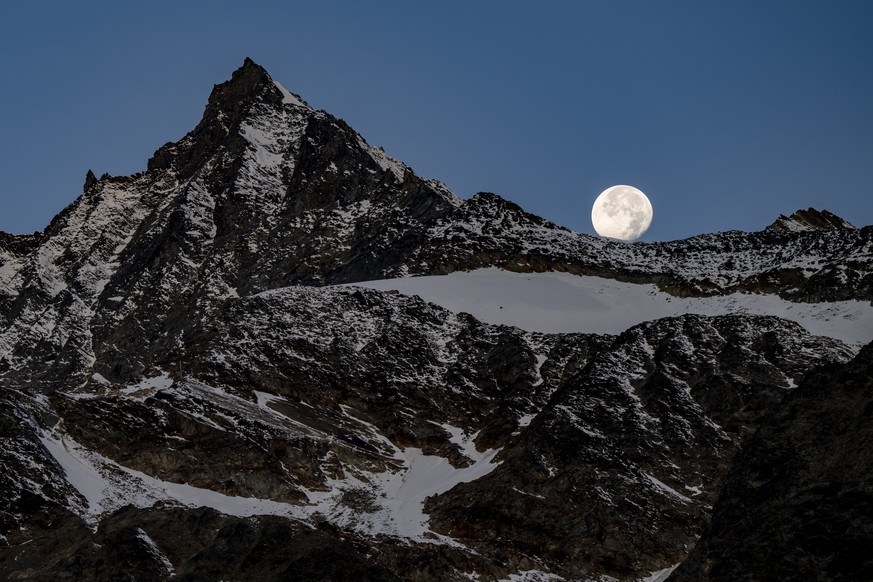 KEYPIX - La Pleine lune est visible au-dessus des montagnes valaisannes le jeudi 9 octobre 2025 a Saas-Fee. (KEYSTONE/Jean-Christophe Bott)