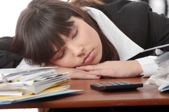 Frau ist am Schreibtisch eingenickt: Eine Schlafapnoe kann zu extremer Schläfrigkeit am Tag bis hin zum unfreiwilligen Einnicken führen. 
