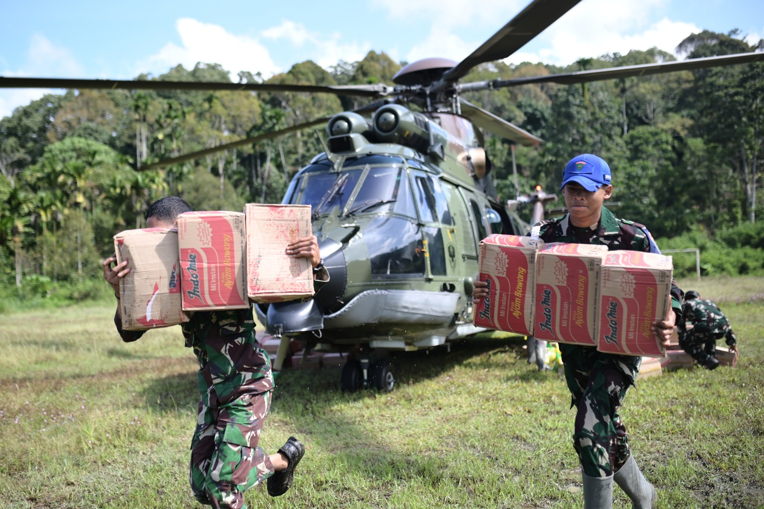 Military personnel unload relief goods from an Indonesian Air Force helicopter during an aid distribution to areas affected by floods in Central Aceh, Indonesia, Saturday, Dec. 6, 2025. (AP Photo/Reza ...