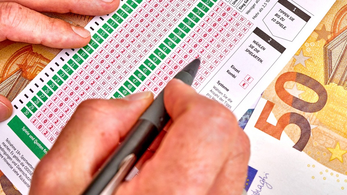 Germany - June 17, 2024: Person fills out compact betting slip from Oddset Sportwette. Lots of banknotes in the background. Sports betting concept for the European Football Championship Euro 2024 in G ...