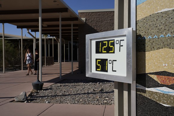 People walk by a thermometer at the Furnace Creek Visitor Center, Thursday, Sept. 1, 2022, in Death Valley National Park, Calif. The thermometer is not official but is a popular photo spot. (AP Photo/ ...
