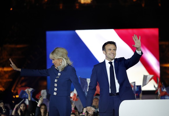 epa09907436 French President Emmanuel Macron and his wife Brigitte Macron celebrate on the stage after winning the second round of the French presidential elections at the Champs-de-Mars after Emmanue ...