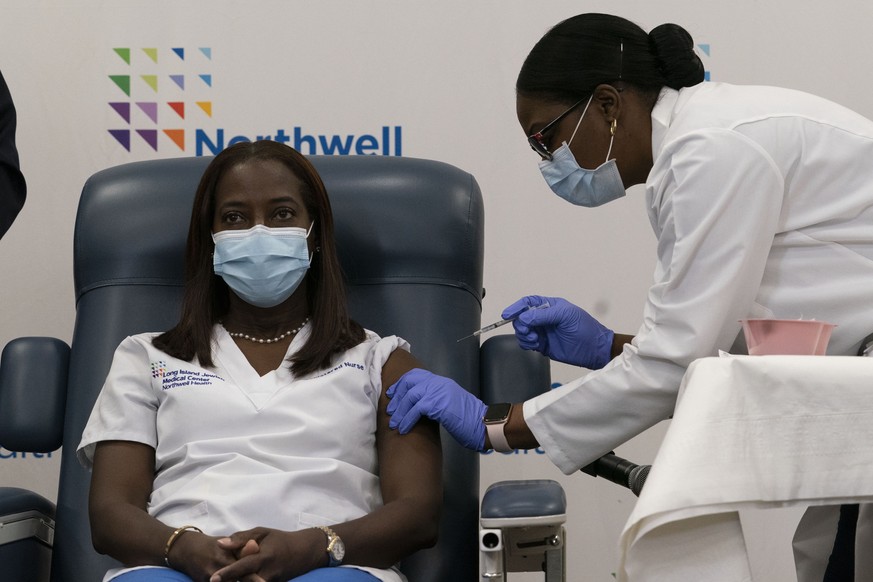 epa08883791 Sandra Lindsay (L) a nurse at Long Island Jewish Medical Center, is inoculated with the COVID-19 vaccine by Dr. Michelle Chester (R) in the Queens borough of New York, New York, USA, 14 De ...