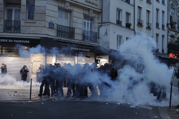 Police officers stand in a cloud of teargas as they clashes with members of Kurdish community near the crime scene where a shooting took place in Paris, Friday, Dec. 23, 2022. Skirmishes erupted in th ...