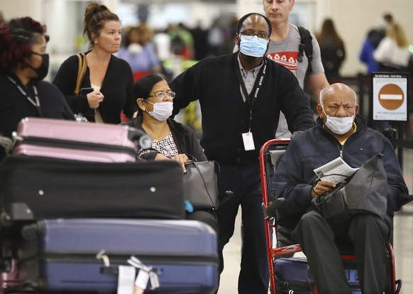 Passengers needing assistance wear masks Monday, March 16, 2020, after returning on a Delta flight from Amsterdam in the International Terminal at Hartsfield Jackson International Airport in Atlanta a ...