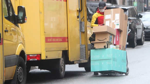 DHL Paketzusteller mit voll beladenem Karren beim Ausliefern von Paketen in der Innenstadt von Frankfurt, Hessen, Deutschland *** DHL parcel deliverer with fully loaded cart delivering parcels in down ...