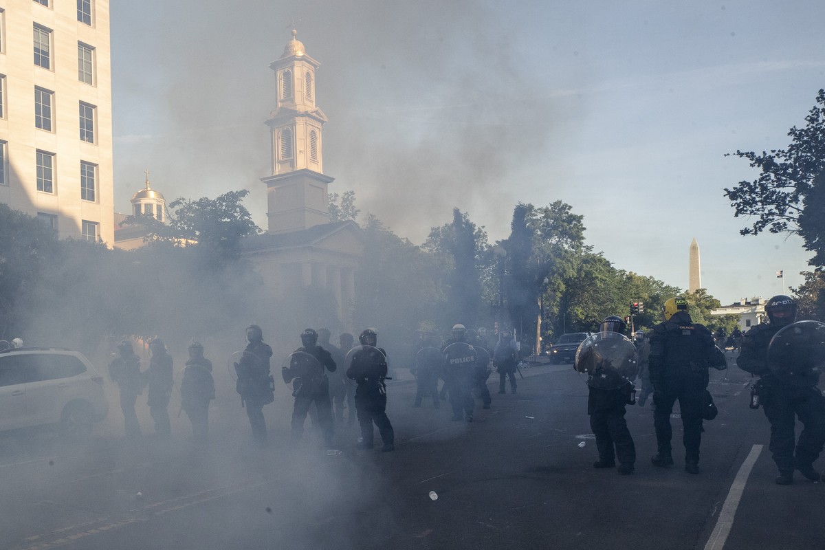 Tear gas floats in the air as a line of police move demonstrators away from St. John's Church across Lafayette Park from the White House, as they gather to protest the death of George Floyd, Mond ...