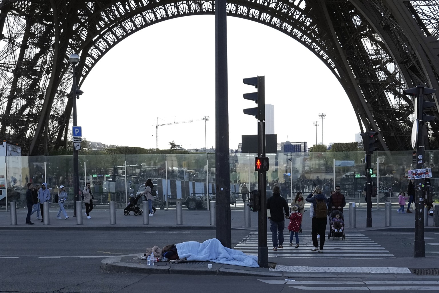 FILE - A homeless sleeps just next to the Eiffel Tower Wednesday, April 10, 2024 in Paris. With the Paris Games 100 days away, French police carried out a large-scale eviction at an abandoned factory, ...