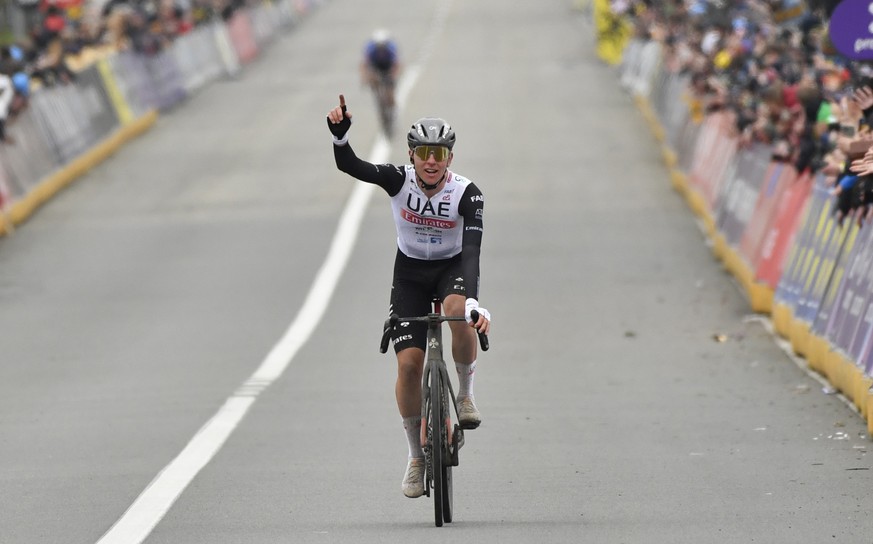 Slovenia&#039;s Tadej Pogacar of the UAE Team Emirates celebrates as he crosses the finish line to win the Tour of Flanders in Oudenaarde, Belgium on Sunday, April 2, 2023. (AP Photo/Geert Vanden Wijn ...