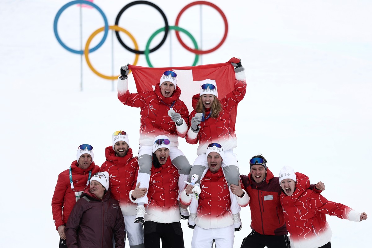 Switzerland's Jon Kistler, top left, and Switzerland's Marianne Fatton celebrate with the team after winning the silver medal in a ski mountaineering mixed relay, at the 2026 Winter Olympics ...