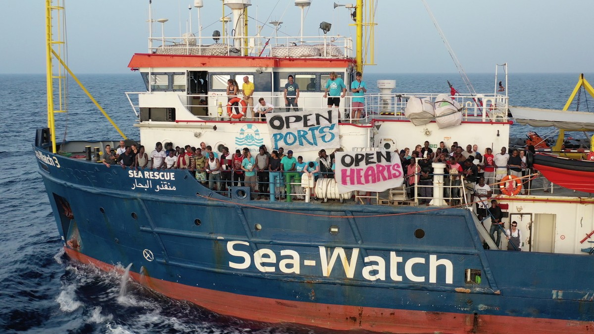 epa07676750 A handout photo made available by Sea-Watch on 27 June 2019 shows migrants holding up banners asking for 'Open Ports' and 'Open Hears' on board the Sea-Watch 3 vessel,  ...