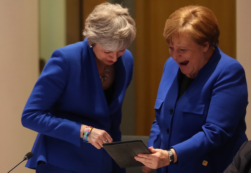 epa07497087 Britain&#039;s Prime minister Theresa May (L) and Germany&#039;s Chancellor Angela Merkel (R) look at a tablet ahead of a European Council meeting on Brexit at the European Council in Brus ...